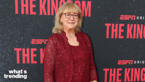 Woman in red lace dress and glasses posing at ESPN The Kingdom event backdrop