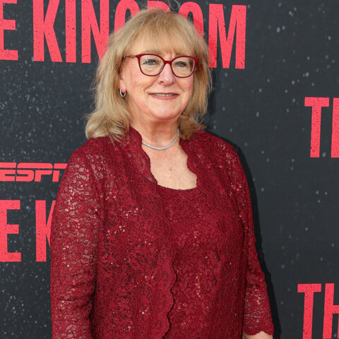 Woman in red lace dress and glasses posing at ESPN The Kingdom event backdrop