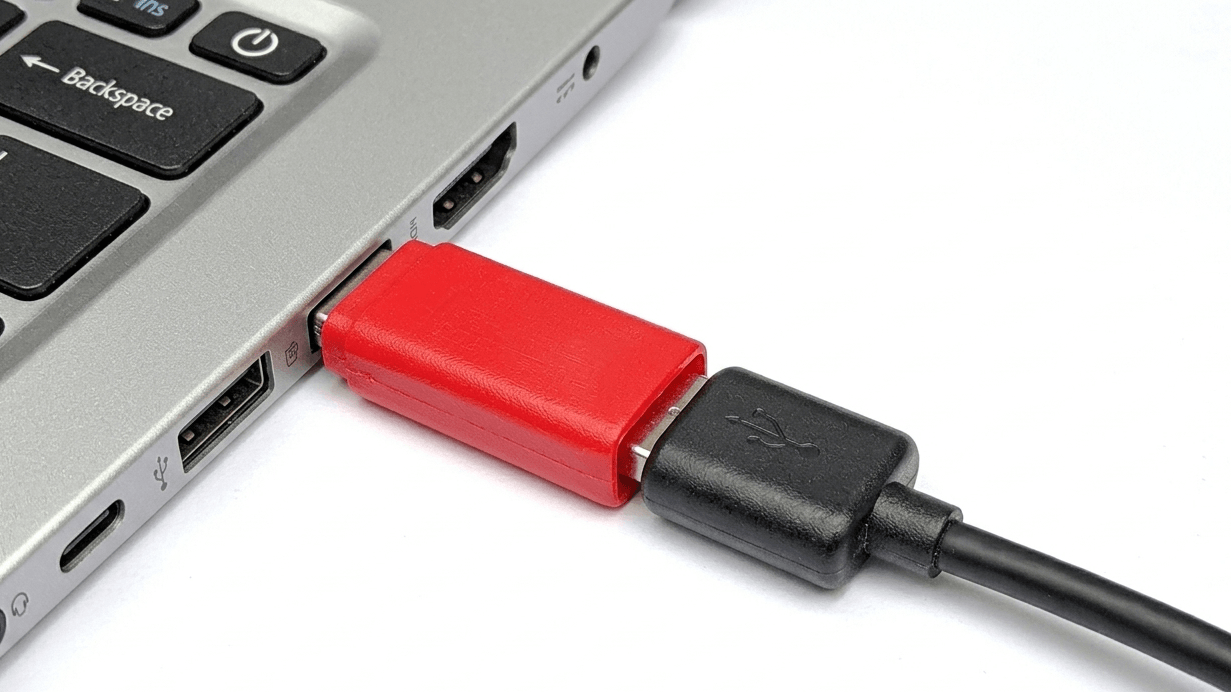 Black USB cable connected to a red USB-C adapter plugged into a laptop USB port