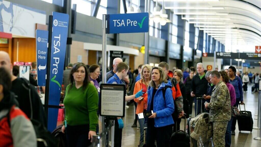 Travelers waiting in line at TSA PreCheck security checkpoint in an airport terminal