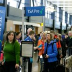 Travelers waiting in line at TSA PreCheck security checkpoint in an airport terminal