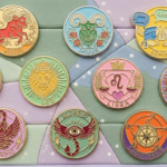 Colorful enamel pins featuring zodiac signs Aries, Taurus, Gemini, Cancer, Leo, Libra, Virgo, Scorpio, and Sagittarius on a pastel background
