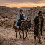 Man leading a donkey carrying a pregnant woman on a rocky path at sunset near an ancient town.