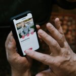 Person using a dating app on a smartphone, viewing a profile named Samantha, 55 years old, with interaction buttons visible.