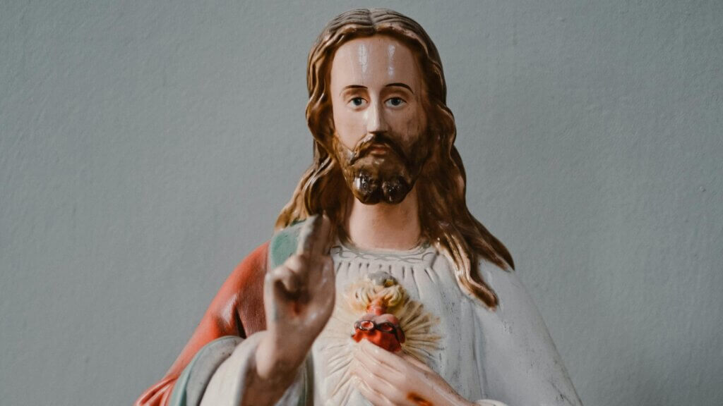Statue of Jesus Christ with Sacred Heart and raised hand against gray background