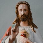 Statue of Jesus Christ with Sacred Heart and raised hand against gray background