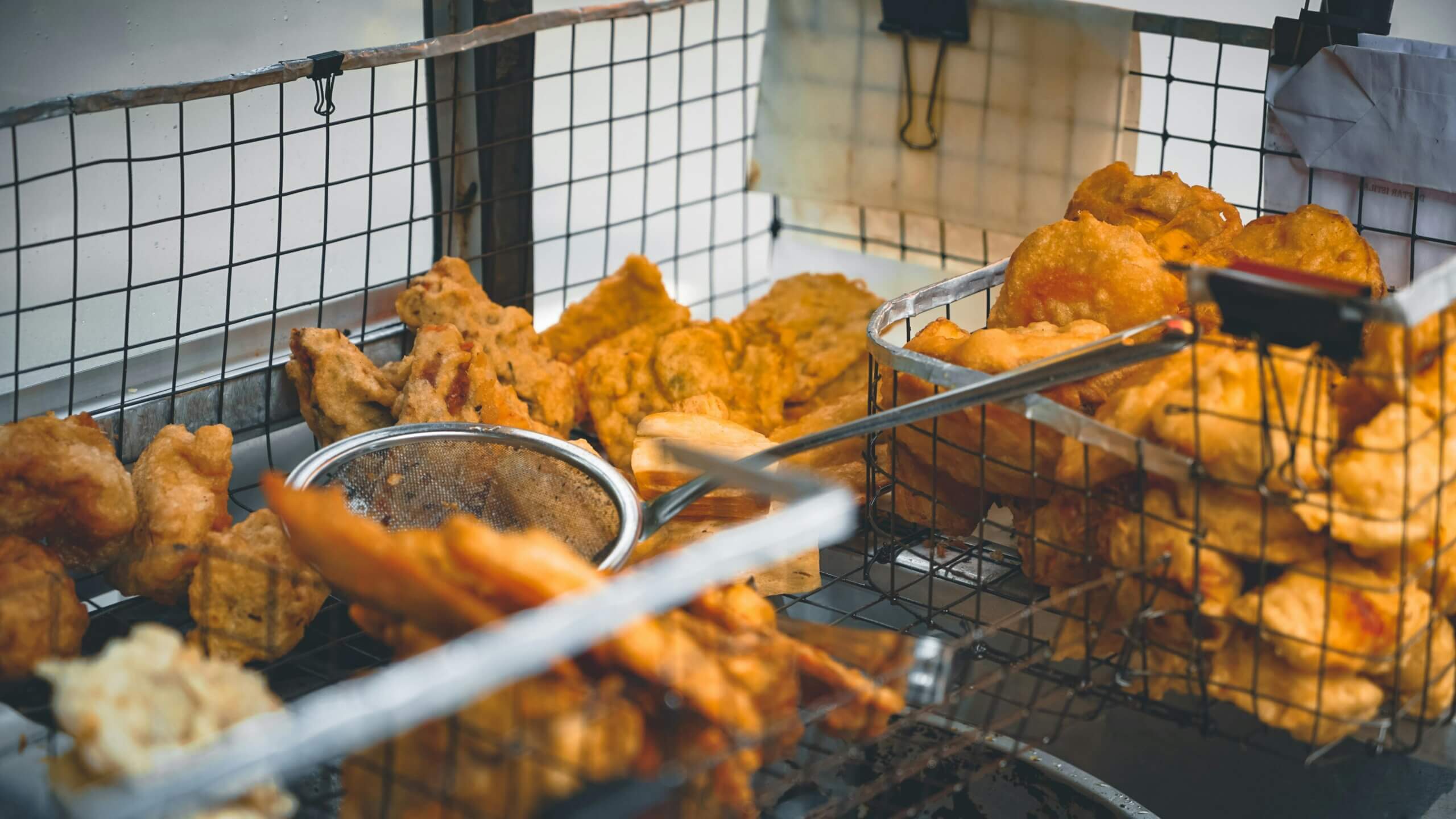 Assorted golden fried snacks in wire baskets at a street food stall