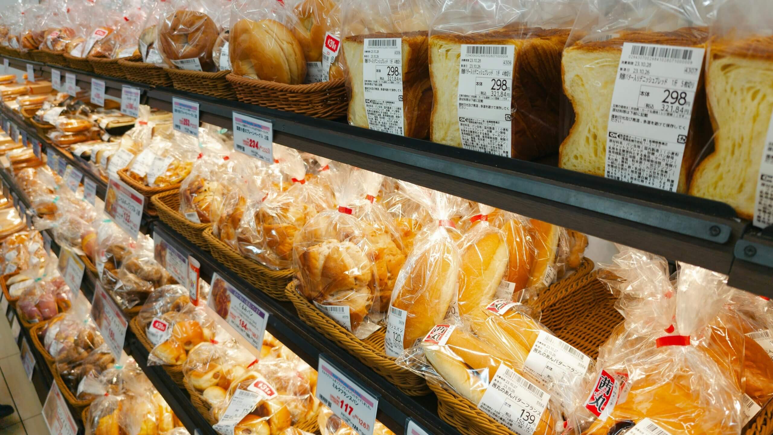 Shelves of various packaged breads and pastries in a Japanese bakery or supermarket.