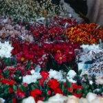 Various colorful flower bouquets including daisies, carnations, and chrysanthemums wrapped in plastic at a market stall