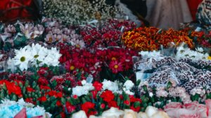 Various colorful flower bouquets including daisies, carnations, and chrysanthemums wrapped in plastic at a market stall