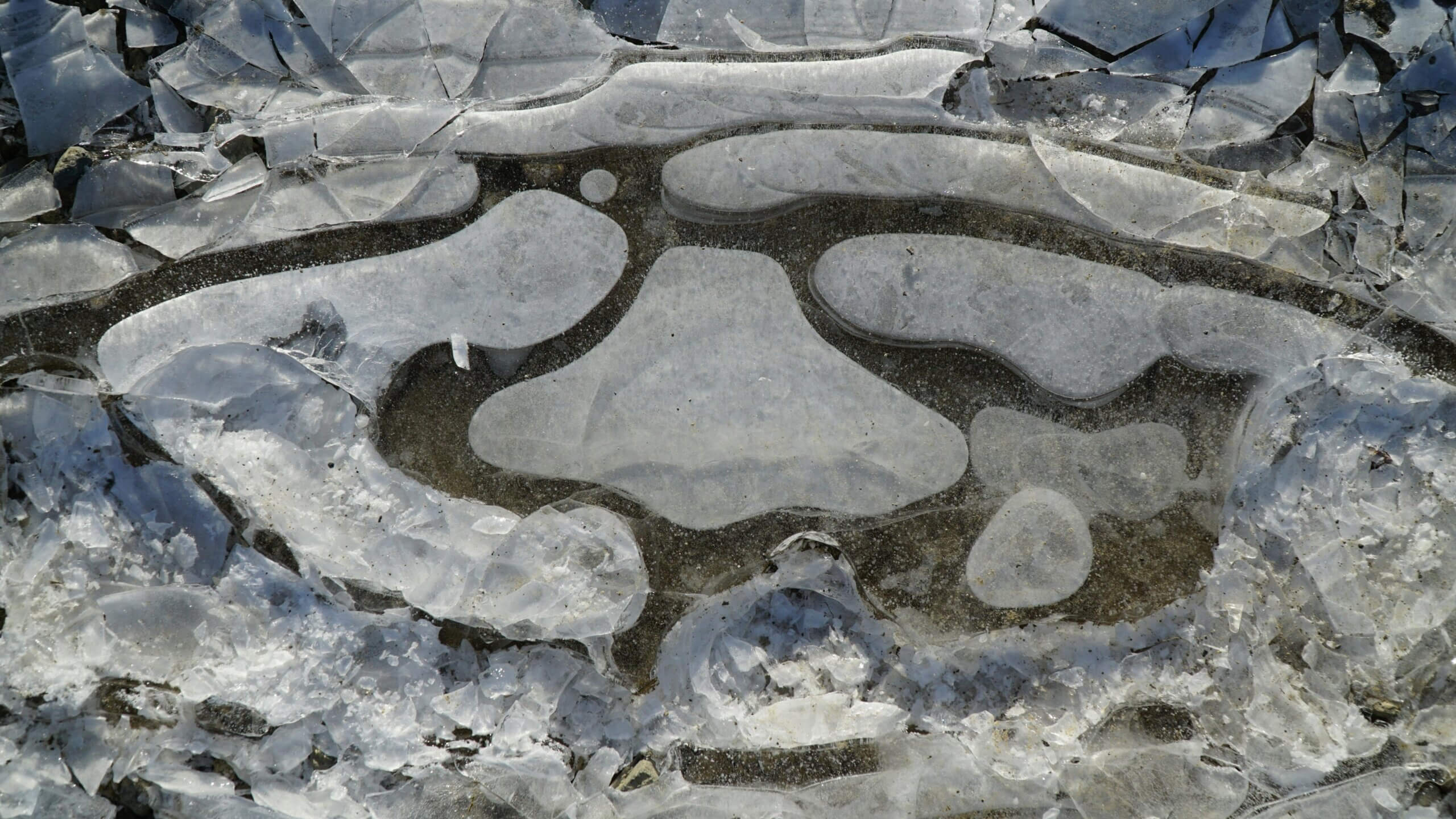 Close-up of cracked and layered ice formations on a frozen surface with varying textures and transparency.