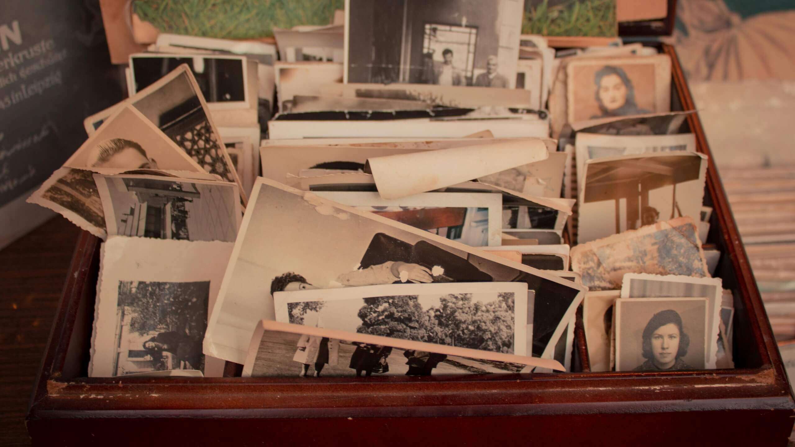 Box filled with old black and white photographs, mostly portraits and group pictures.