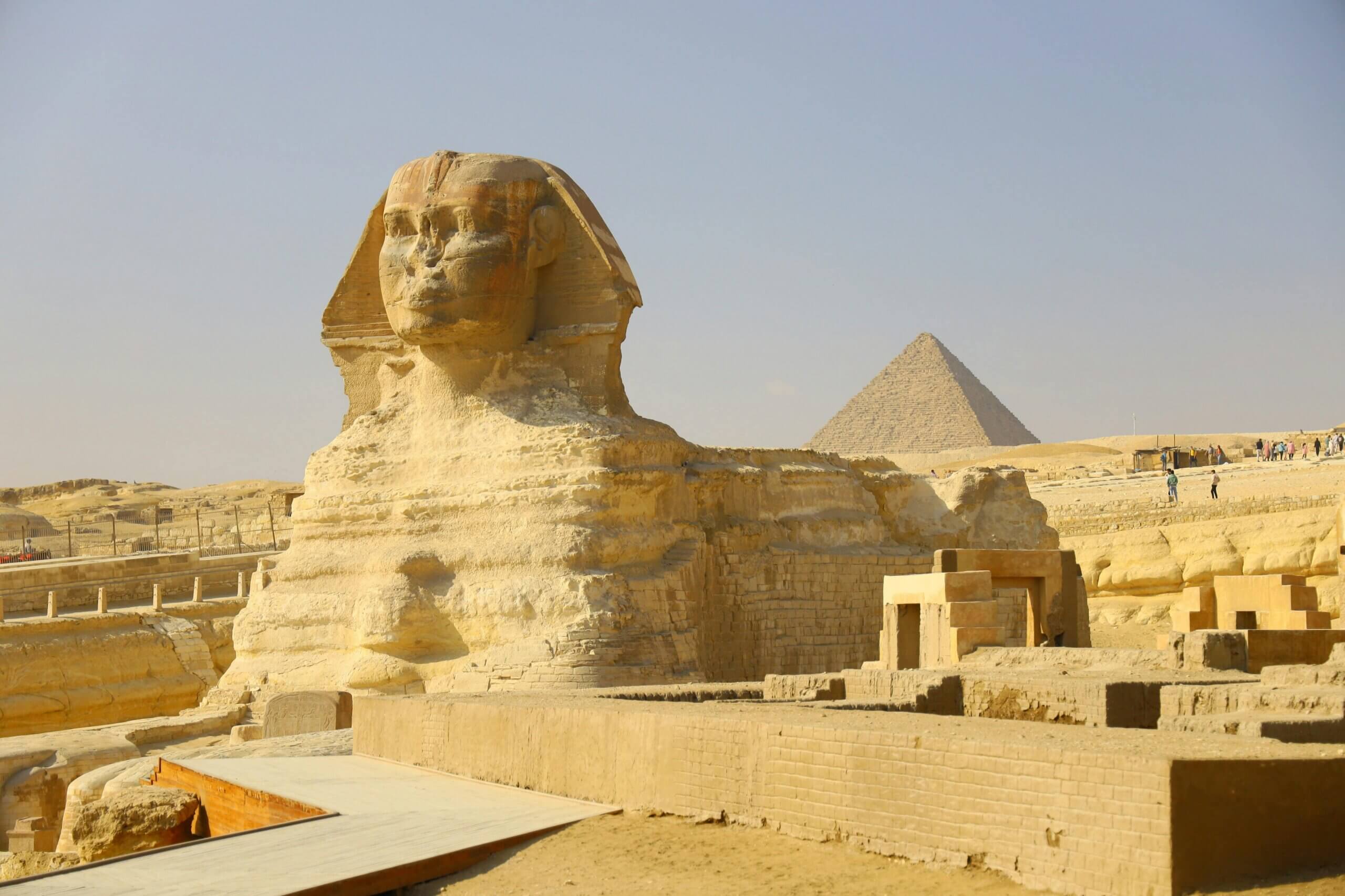 The Great Sphinx of Giza with the Pyramid of Khafre in the background under a clear sky.