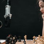 Woman in white shirt playing chess against a robotic arm on a wooden chessboard