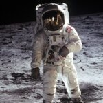 Astronaut Buzz Aldrin in a spacesuit standing on the moon with lunar surface and black sky background