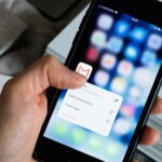 Hand holding iPhone with Gmail app options menu open on screen