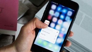 Hand holding iPhone with Gmail app options menu open on screen