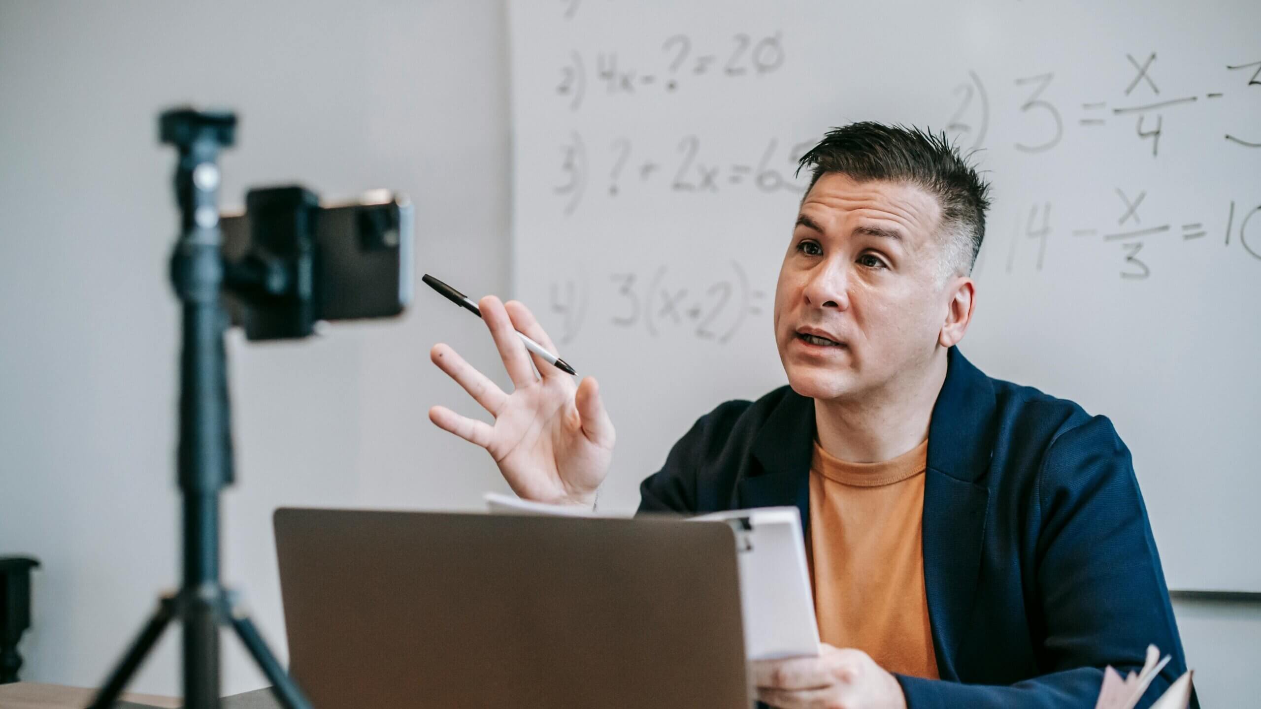 Man teaching math equations on whiteboard during online lesson recorded on smartphone tripod