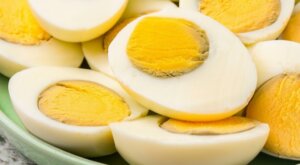 Close-up of halved hard-boiled eggs with firm yolks on a green plate.