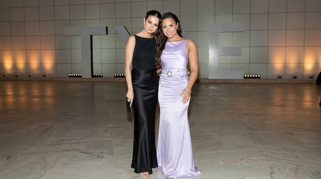 Selena Gomez and Demi Lovato posing together in elegant evening gowns at a formal event.