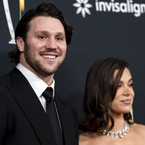 Man in black suit and tie smiling next to woman with shoulder-length hair and diamond necklace at event with Invisalign logo background