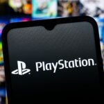PlayStation logo displayed on a smartphone screen with blurred video game covers in the background.
