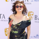 Susan Sarandon smiling in floral off-shoulder dress and red sunglasses at BAFTA Television Awards 2023