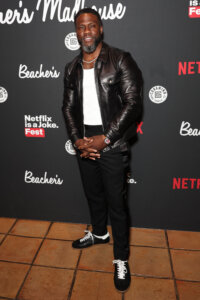 Kevin Hart wearing a black leather jacket and white shirt at Netflix is a Joke Fest event backdrop
