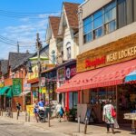 Street view of people walking past shops including Springfield Meat Locker with red and blue awnings on a sunny day