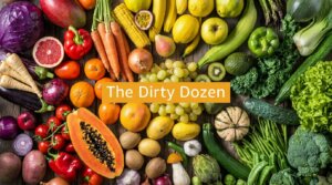 Variety of fruits and vegetables arranged around the text "The Dirty Dozen" on a wooden surface