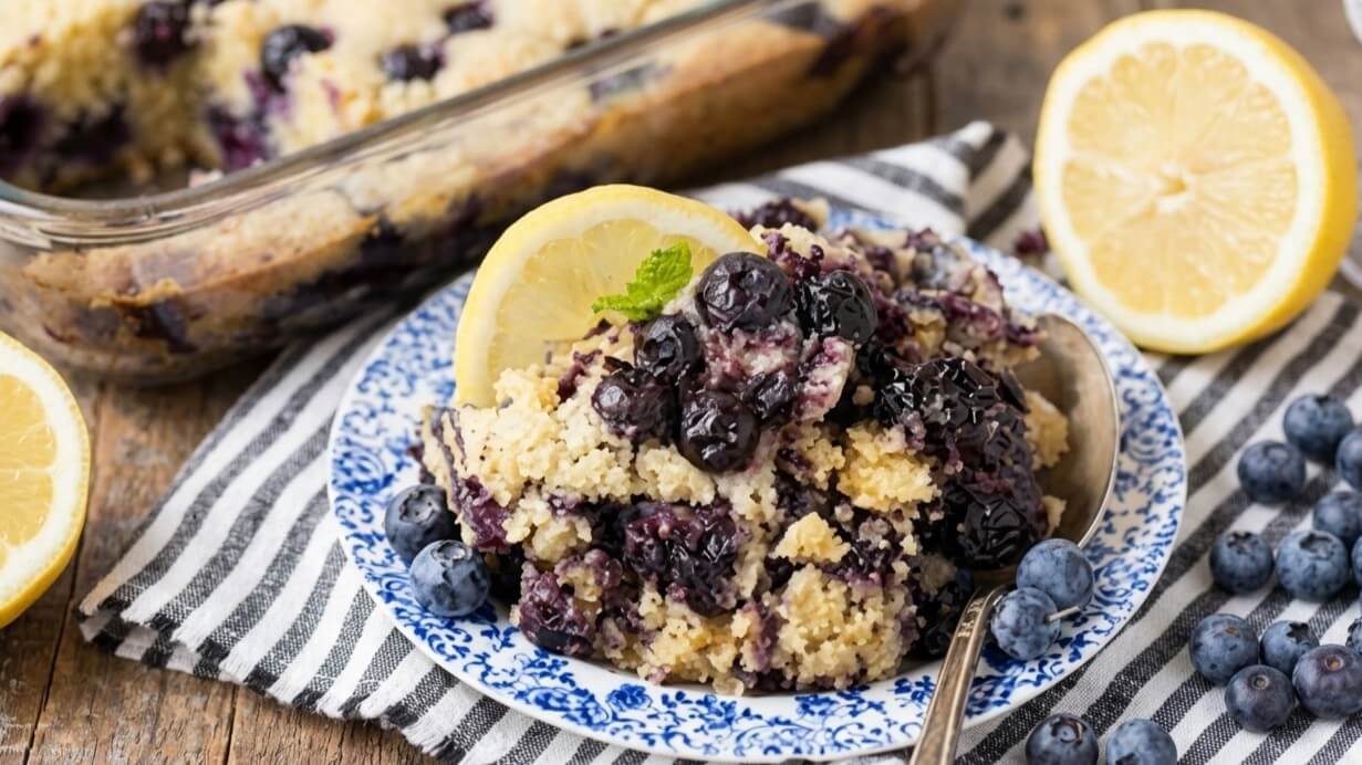 Blueberry lemon couscous served on a blue and white plate with fresh blueberries and lemon slices nearby.