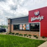 Wendy's fast food restaurant exterior with American flag and promotional posters on windows.