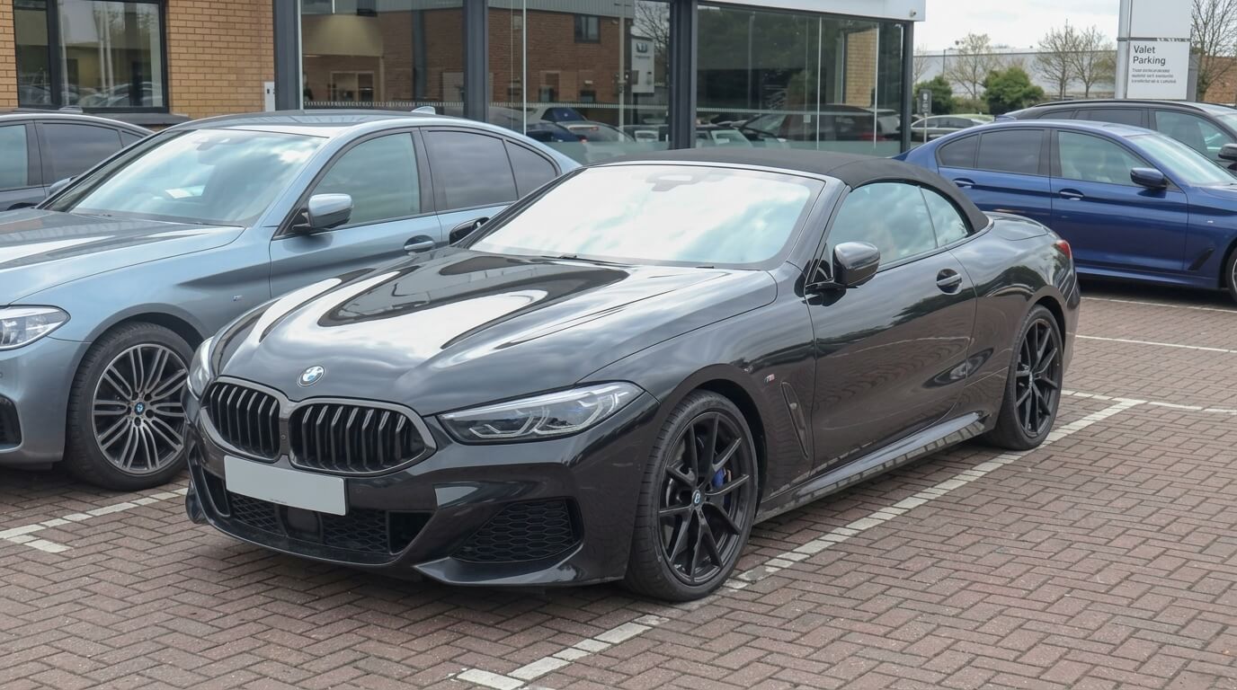 Black BMW convertible parked in a lot with other BMW cars nearby