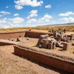 Ruins of the Pumapunku archaeological site with large stone blocks under a blue sky.