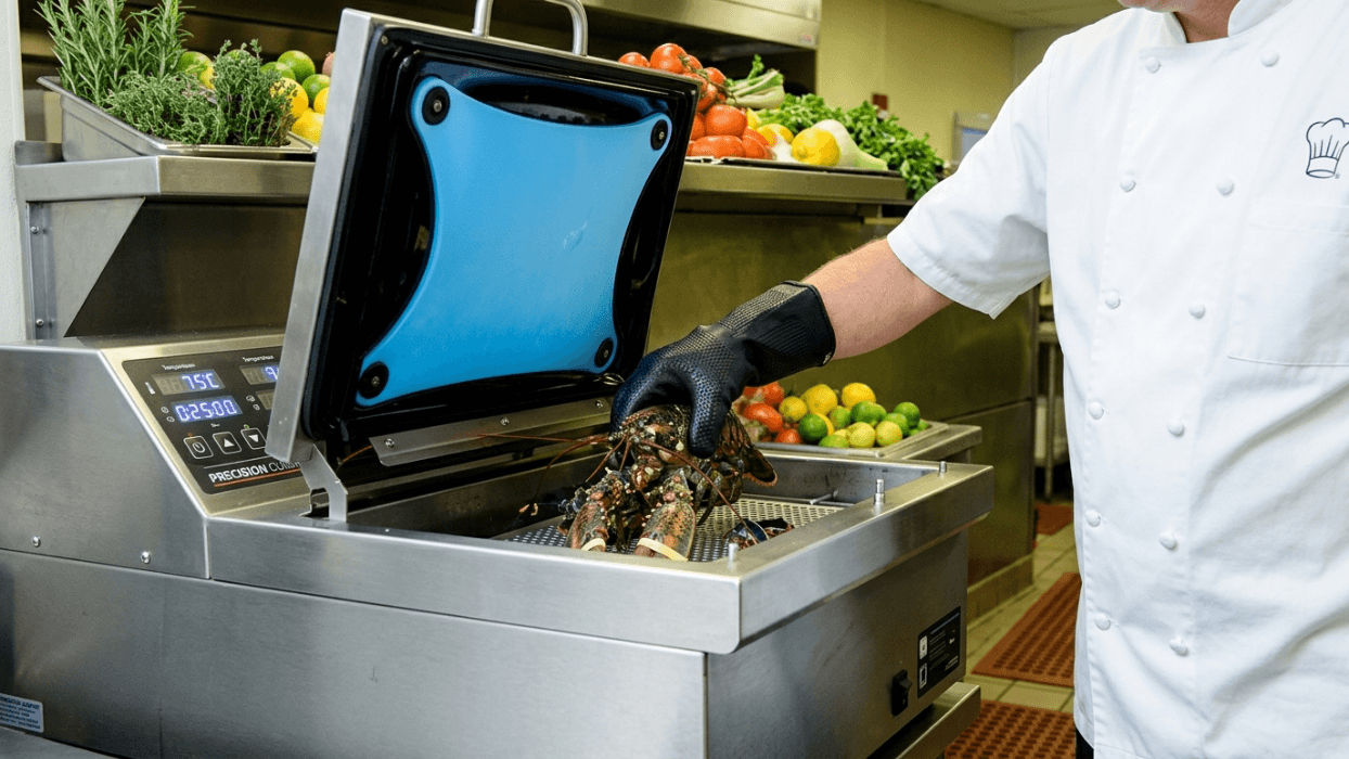 Chef placing live lobsters into a Precision Cooker sous vide machine in a commercial kitchen