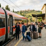 Train conductor greeting passengers boarding the Frecciarossa train at Val d'Orcia Castello station in Italy.