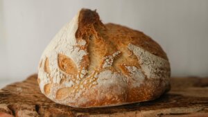 Round loaf of rustic sourdough bread with a cracked crust on a wooden surface