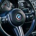 BMW steering wheel with M Sport stitching and dashboard controls in a car interior.