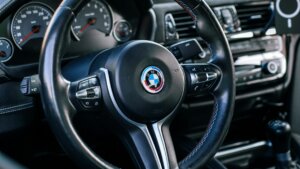 BMW steering wheel with M Sport stitching and dashboard controls in a car interior.