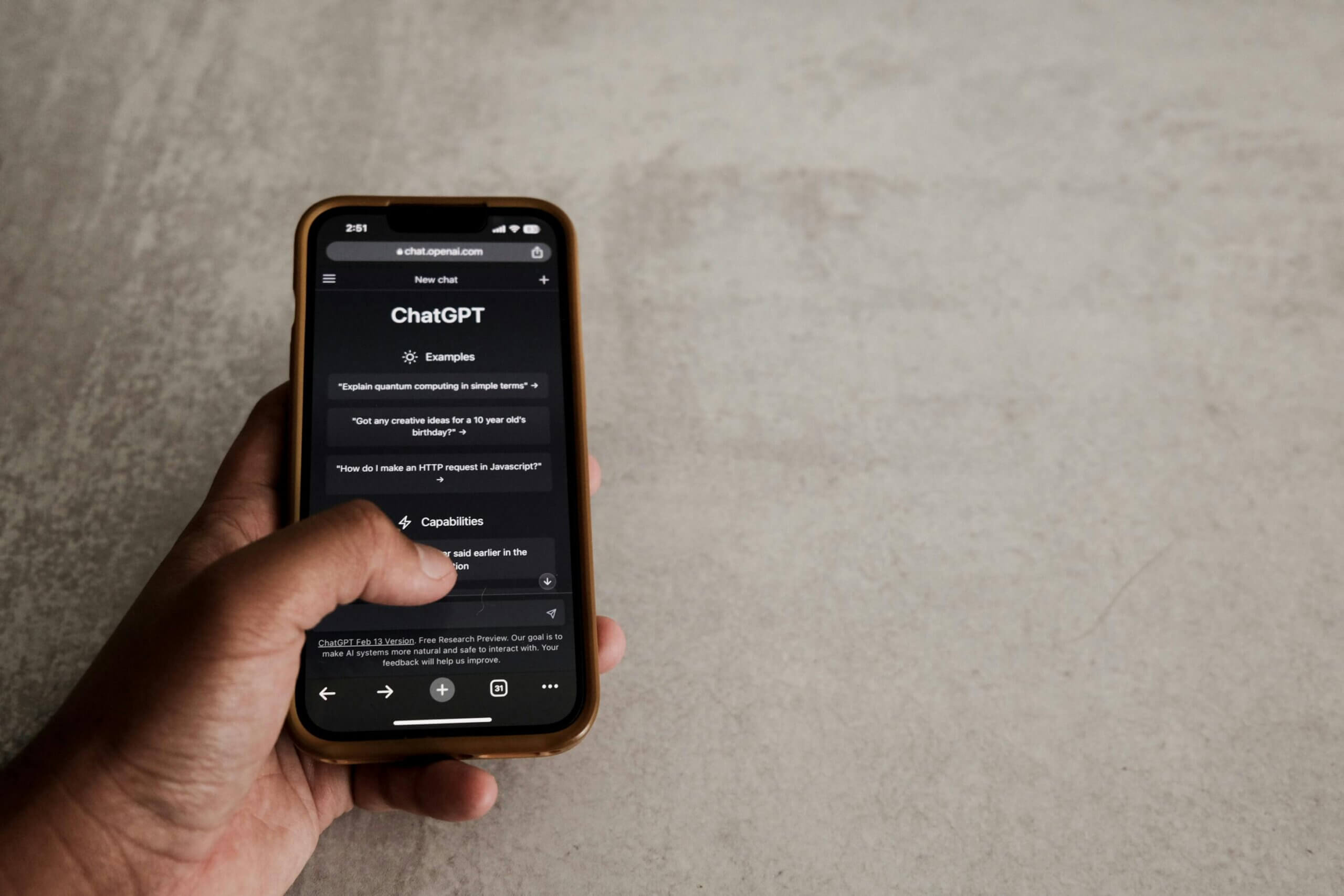 Hand holding smartphone displaying ChatGPT interface on chat.openai.com website.