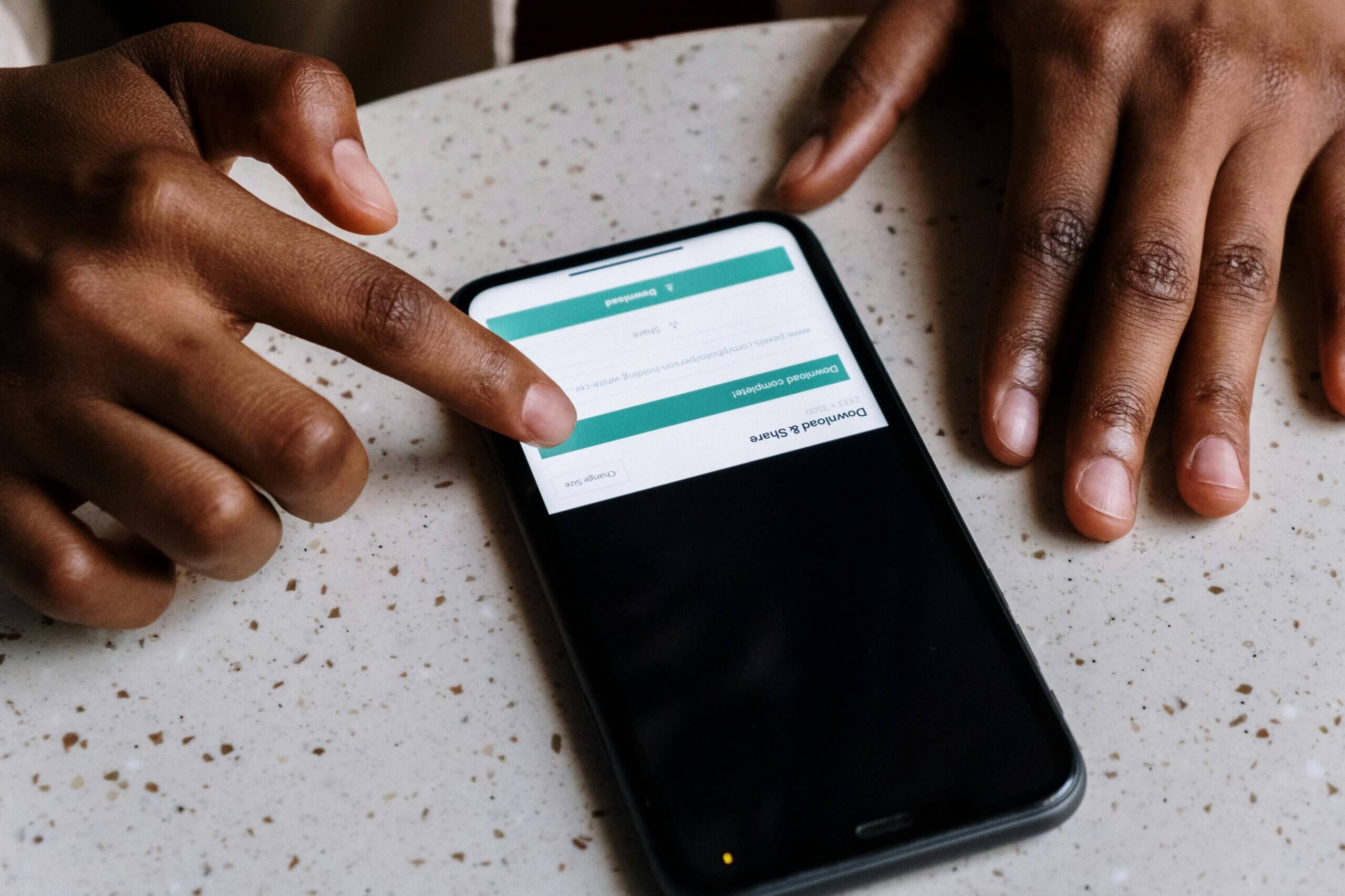 Person's hand interacting with a smartphone screen showing a "Download & Share" confirmation message.