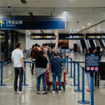 Passengers waiting in line at an airport security checkpoint near Terminal 2 signs in Chinese and English