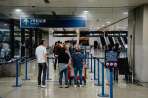 Passengers waiting in line at an airport security checkpoint near Terminal 2 signs in Chinese and English