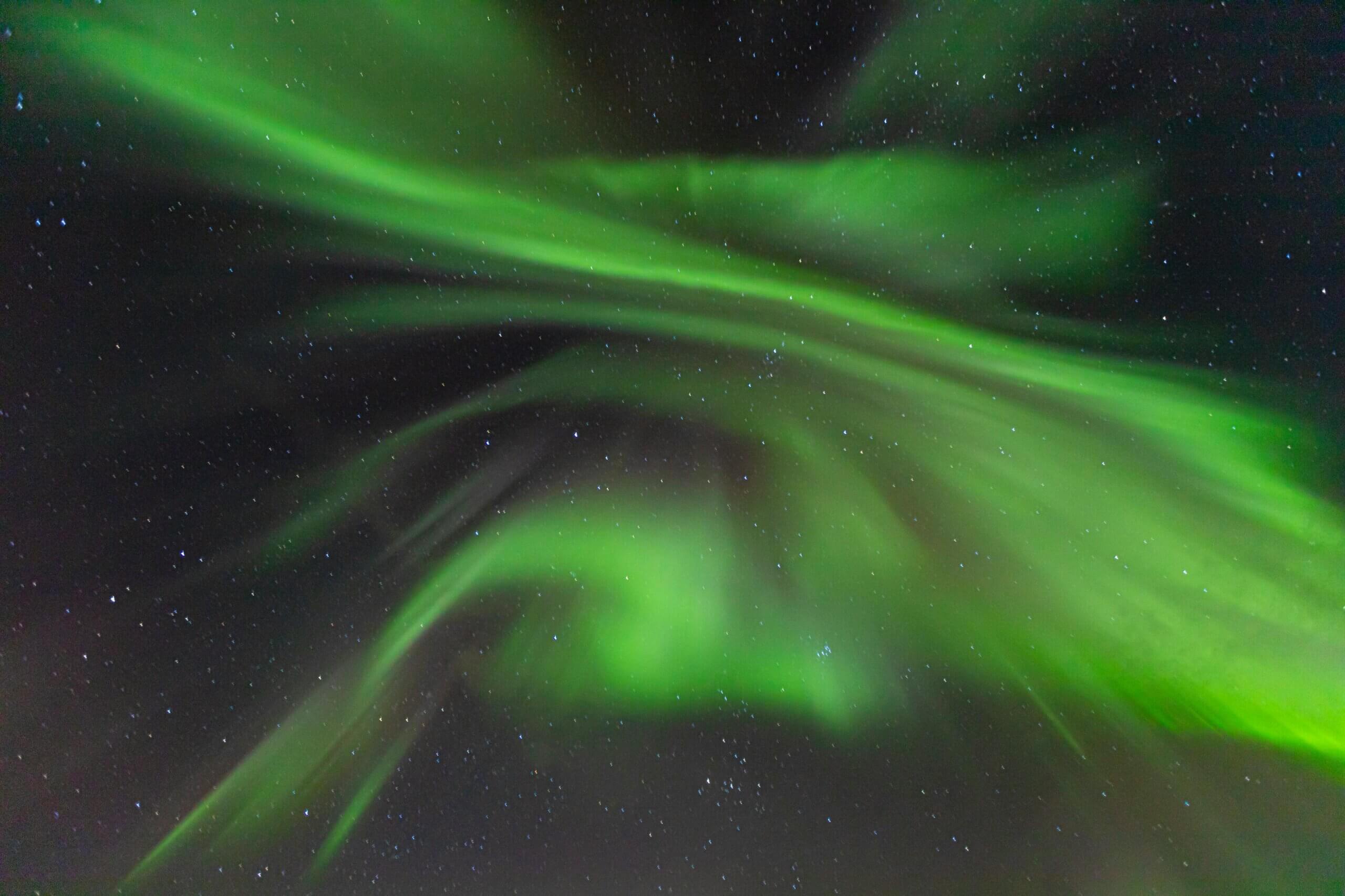 Green northern lights swirling across a starry night sky.