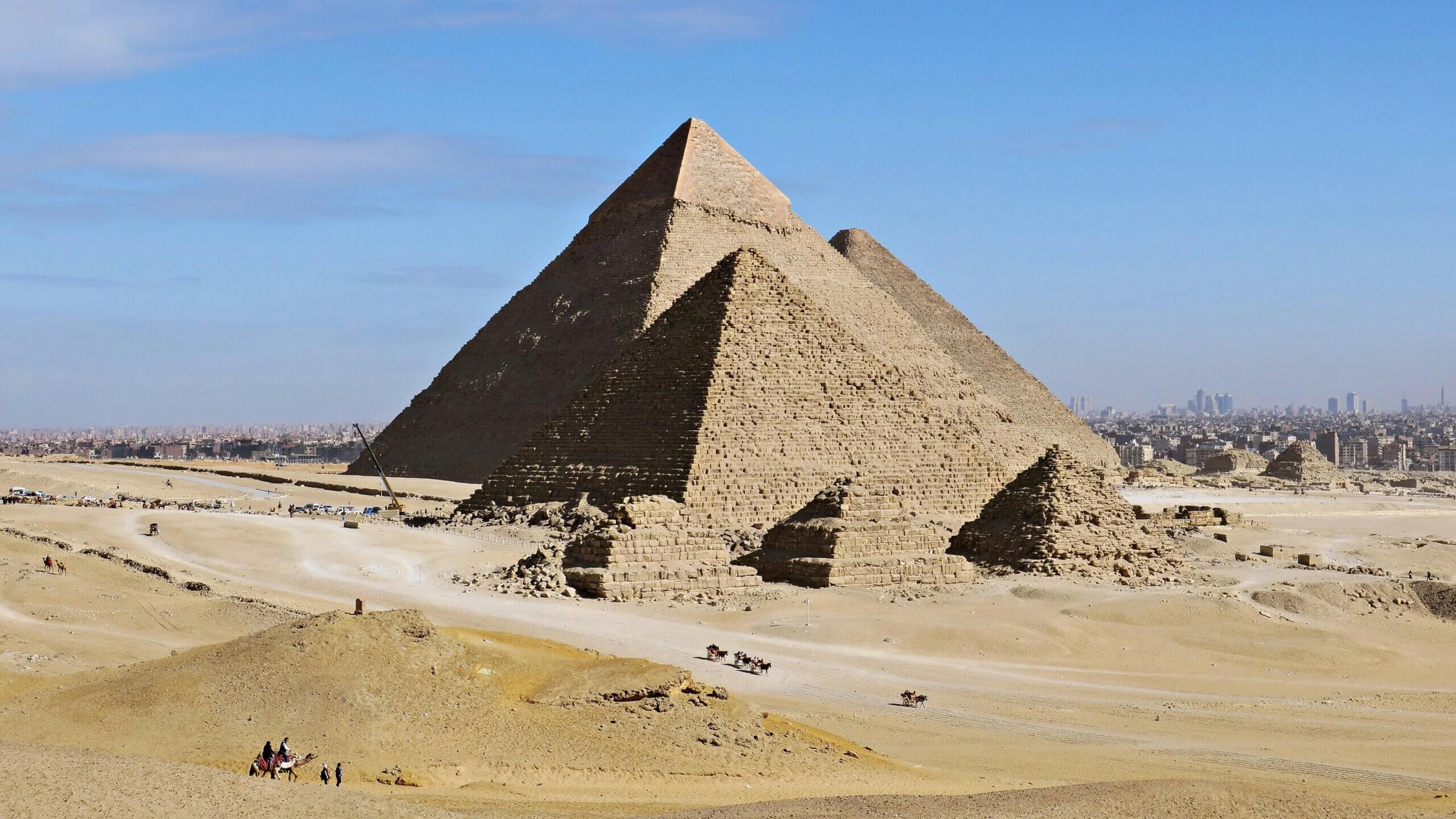 The Great Pyramids of Giza with camels and people in the desert near Cairo, Egypt.