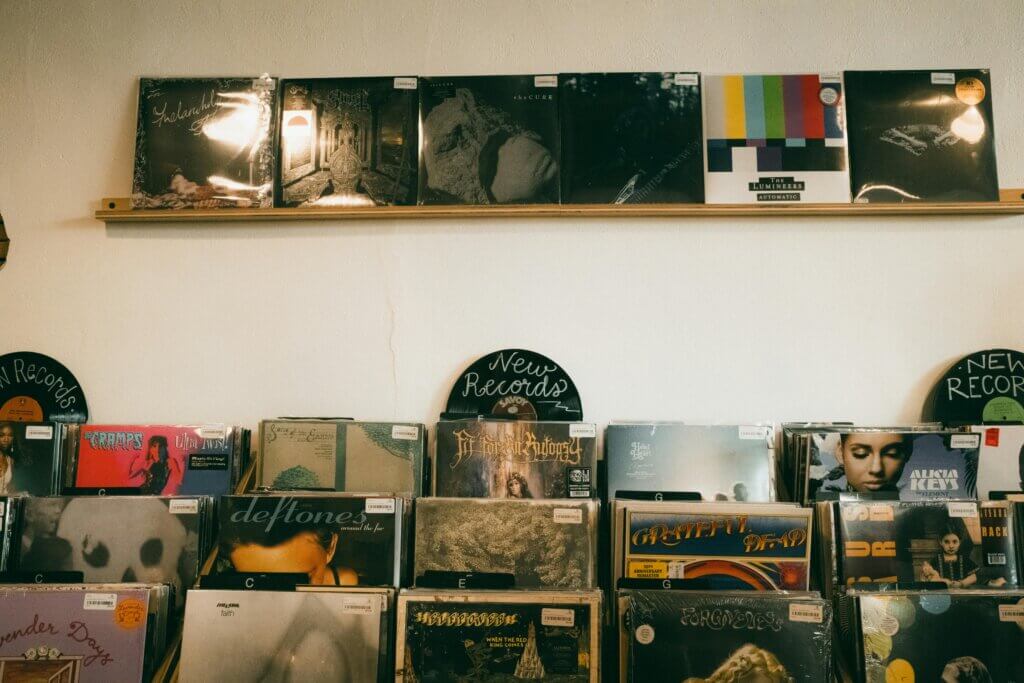 Vinyl records displayed on shelves in a record store, featuring albums by The Lumineers, Deftones, and Alicia Keys.