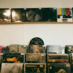 Vinyl records displayed on shelves in a record store, featuring albums by The Lumineers, Deftones, and Alicia Keys.