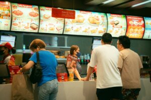 Customers ordering at a Jollibee fast food counter with menu boards displaying meals above.