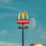 McDonald's golden arches sign with "Automac" under a clear blue sky