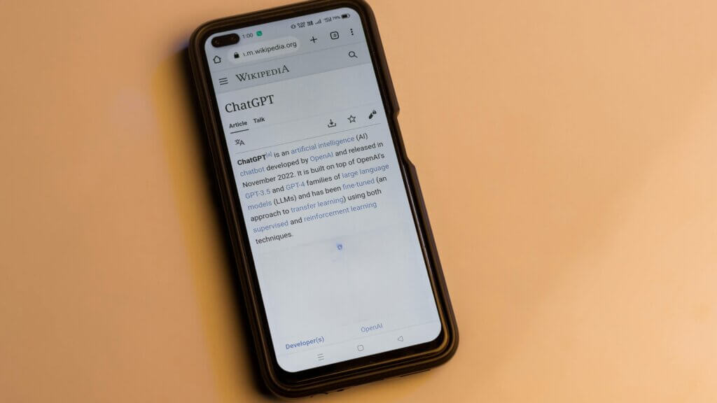 Smartphone displaying the Wikipedia page for ChatGPT on a beige surface.